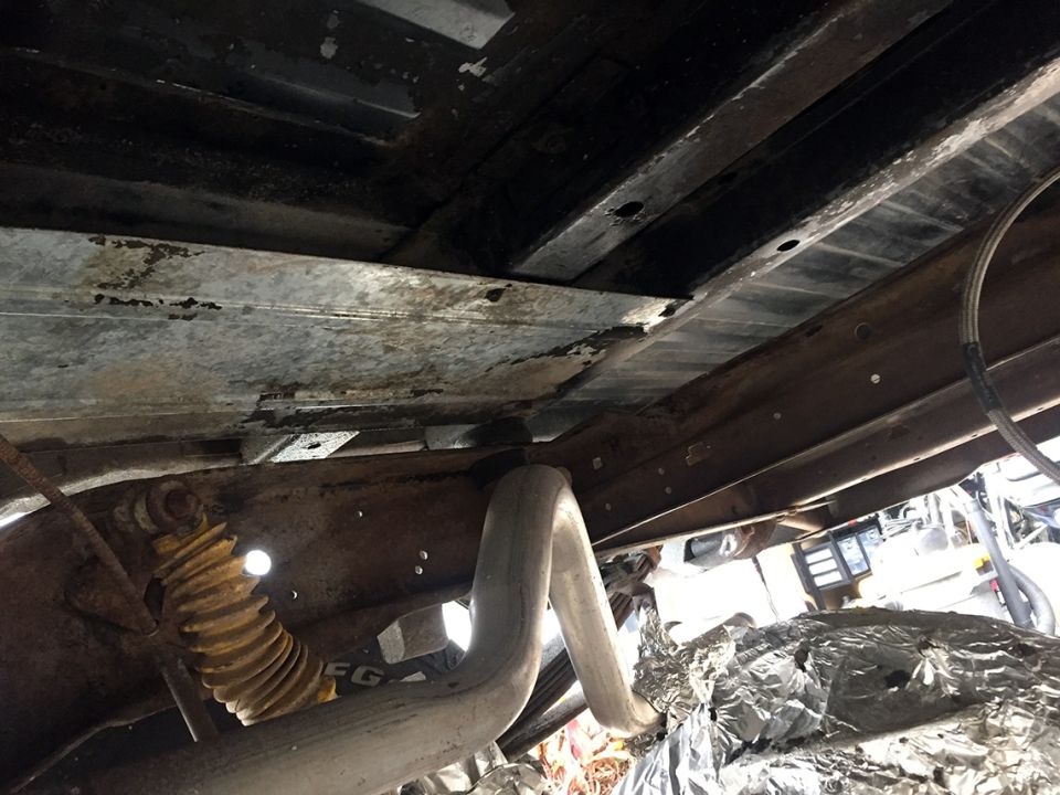 Undercarriage of a 1978 Ford Bronco showing yellow shock and exhaust pipe
