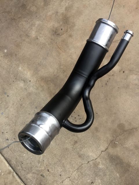 1978 Ford Bronco - A black fuel filler neck with silver metal ends is shown against a concrete surface.