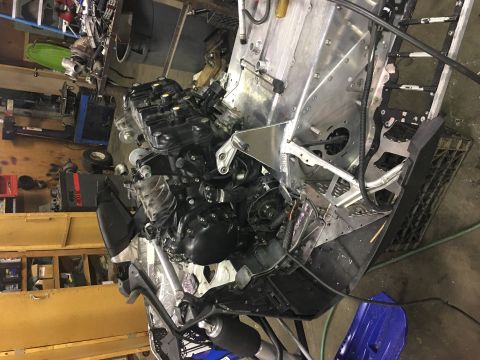 2000 Ford E350 - The engine and frame of a snowmobile are visible in a garage setting, with tools and other parts in the background.