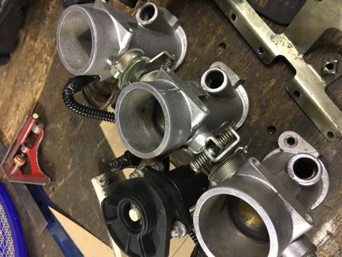 2000 Ford E350 - Close-up view of multiple throttle bodies, likely for an engine, resting on a workbench.