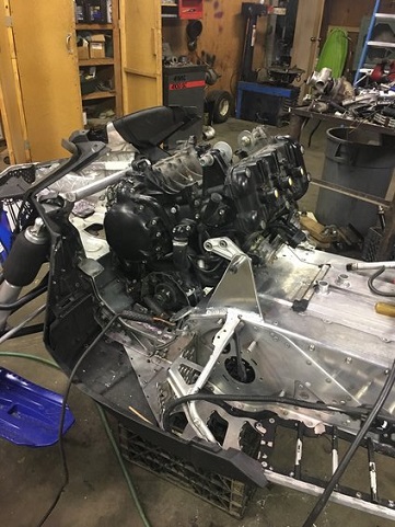 2000 Ford E350 - A snowmobile's chassis and engine are visible in a workshop setting, with various tools and parts in the background.