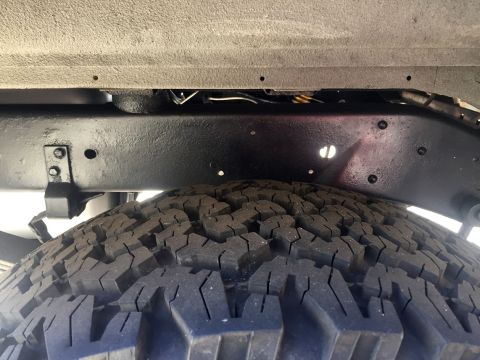 1978 Ford Bronco - Close-up view of the undercarriage frame and tire tread of a vehicle.