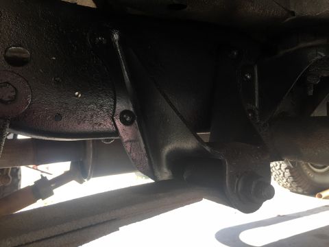 1978 Ford Bronco - Underside view of a glossy black-painted front axle differential housing with leaf spring and tire visible.