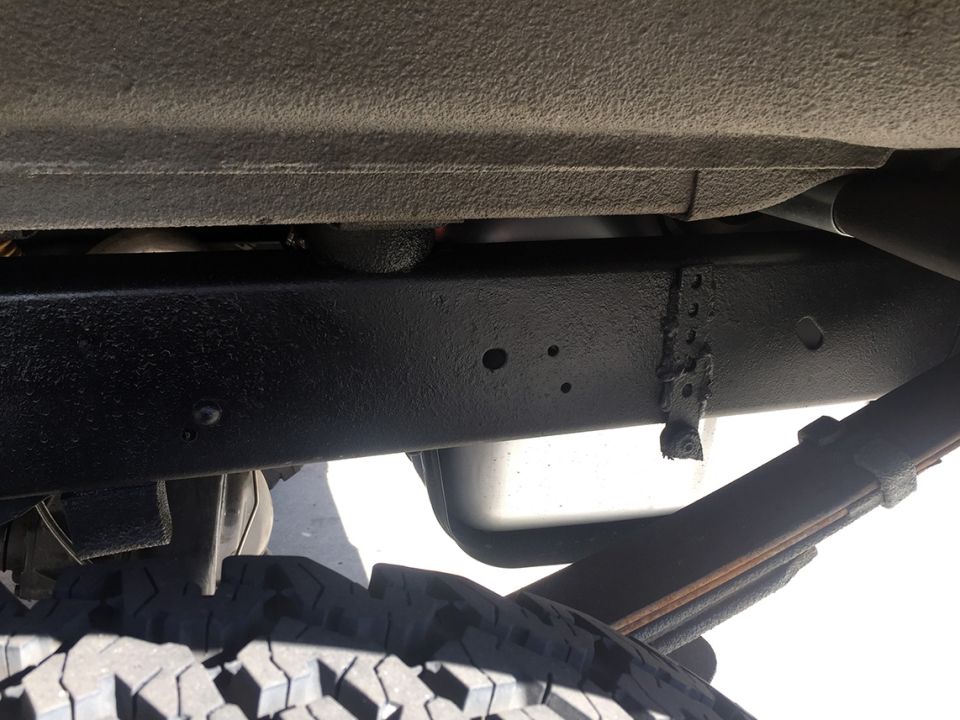 Undercarriage view showing frame rail, leaf spring, and tire tread