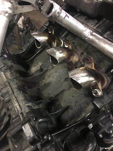 2000 Ford E350 - The exhaust manifold shows signs of wear and tear, with multiple pipes leading away from the engine block.