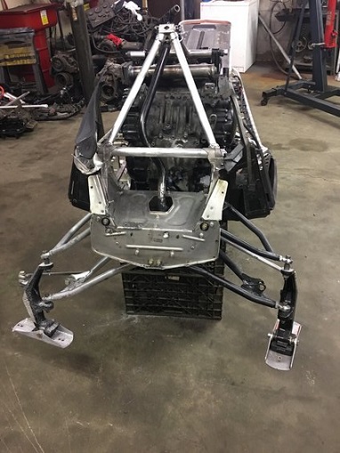 2000 Ford E350 - The front suspension and engine assembly of a snowmobile are displayed in a workshop setting.
