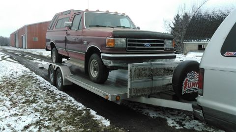 1991 Ford F-150 - A maroon 1991 Ford F-150 with a camper shell is loaded onto a trailer.