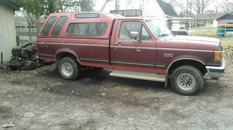 Maroon 1991 Ford F-150 with a red camper shell, seen from the side at a 3/4 front angle