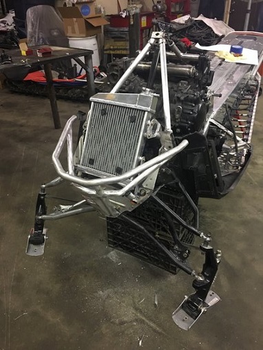 2000 Ford E350 - The front end of a snowmobile is shown with its engine and radiator assembly in a workshop setting.