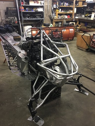 2000 Ford E350 - A snowmobile chassis with its engine and front suspension is shown in a workshop setting.