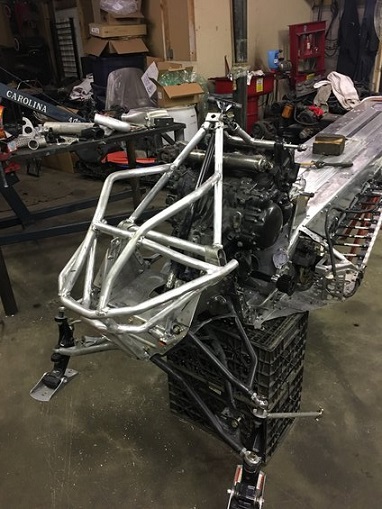 2000 Ford E350 - A snowmobile chassis and engine assembly is shown in a workshop setting, supported by black crates.
