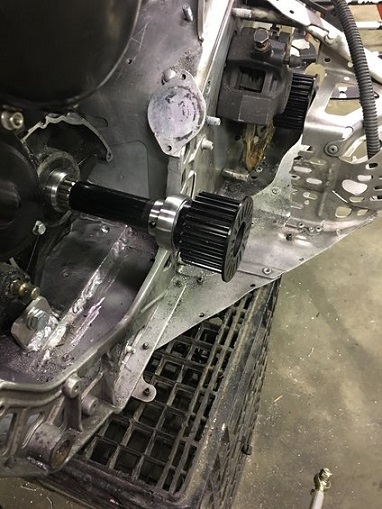2000 Ford E350 - Close-up of a snowmobile's drivetrain, showing a drive shaft and cogwheel assembly.