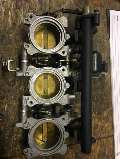 2000 Ford E350 - A throttle body assembly with three butterfly valves is shown, likely a component from a vehicle's engine system.