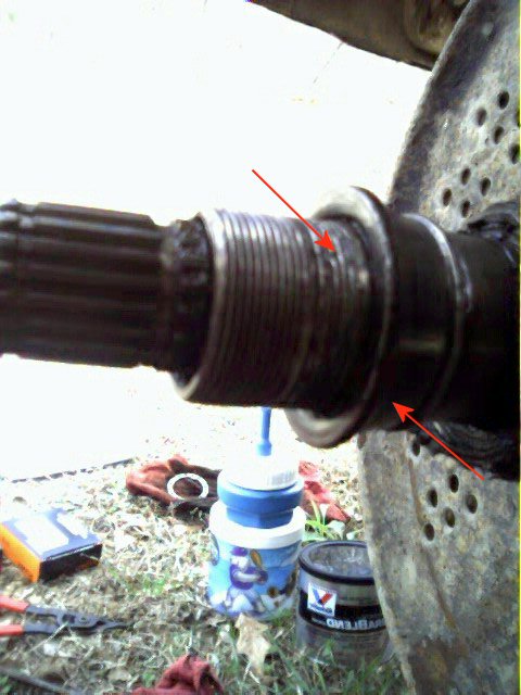 1986 Ford Bronco - Close-up of a vehicle's splined axle shaft, showing wear on the threaded portion, with tools and a fluid container nearby.