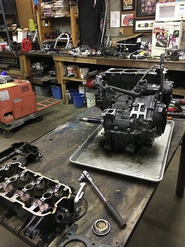 2000 Ford E350 - Engine components and tools are laid out on a workbench in a repair shop.
