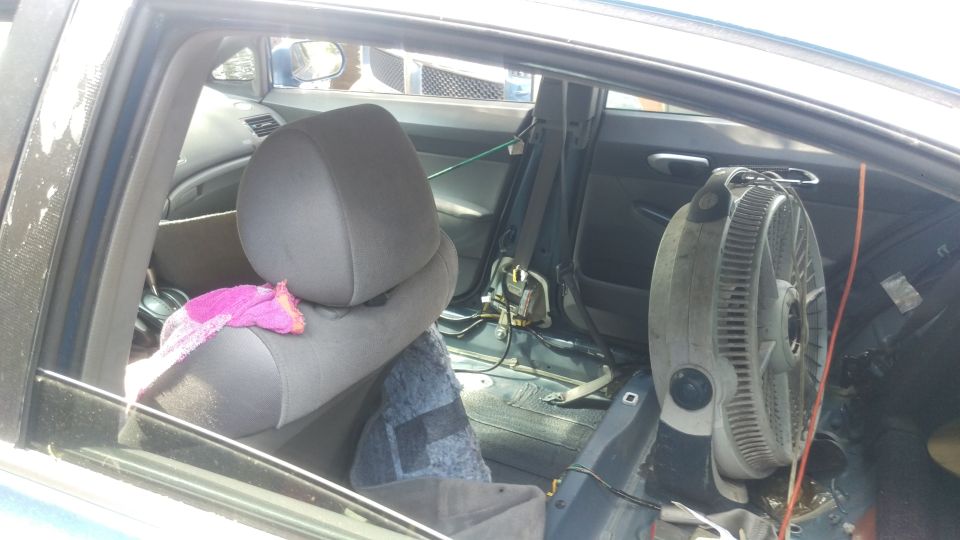 Car interior with seats, fan mounted, and some debris on the floor. Supermotors.net logo visible