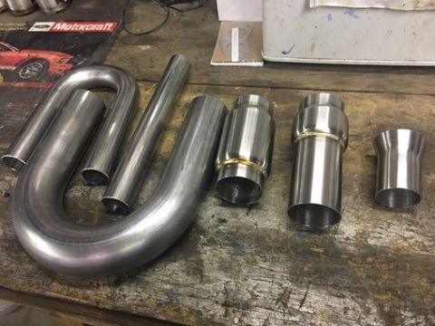 2000 Ford E350 - A collection of exhaust pipe components, including U-bends and mufflers, laid out on a workbench. The 'Motorcraft' logo is visible in the b…