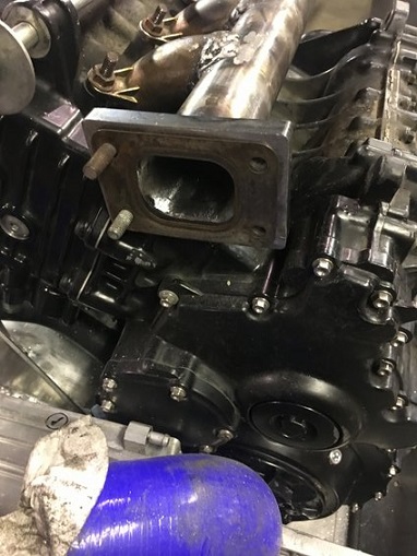 2000 Ford E350 - Close-up of an engine component, possibly a turbocharger exhaust manifold, with visible bolts and metalwork.
