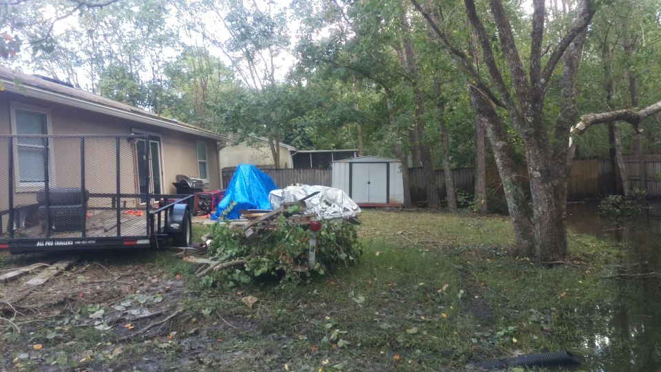 Backyard with a trailer, debris, and a shed. Water is visible on the right side