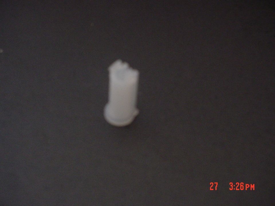 Blurry close-up of a small white nylon bushing on a dark background, likely a transfer-case part