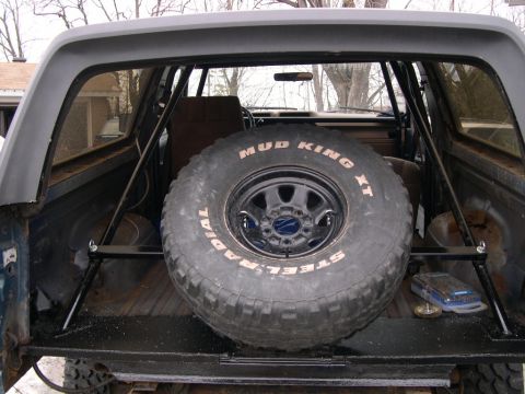 1986 Ford Bronco - Spare tire with 'Mud King XT' and 'Steel Radial' text is secured inside the vehicle's rear compartment.