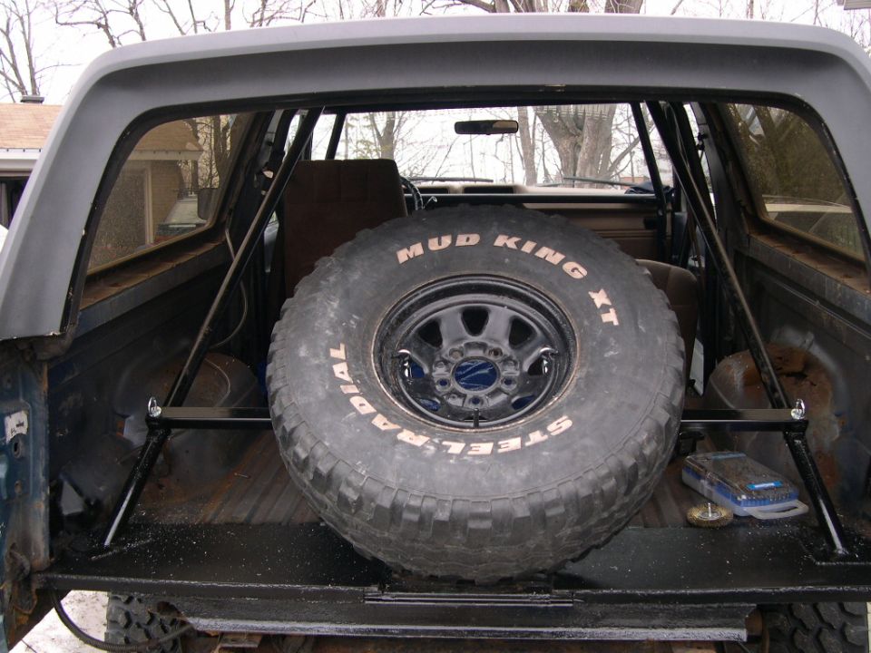 Spare tire mounted inside a vehicle's cargo area with a roll cage visible