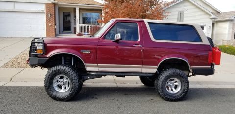 1996 Ford Bronco - Side view of a lifted 1996 Ford Bronco with a two-tone paint job and a red jerry can mounted on the rear.