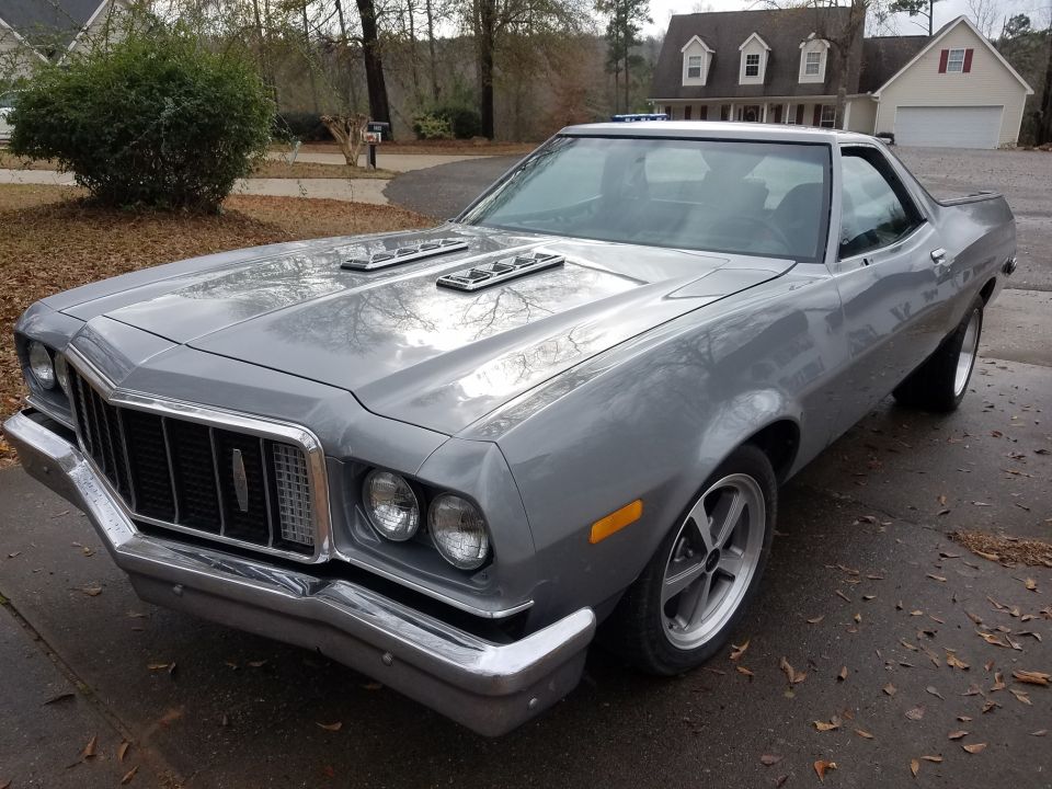 1976 Ford Ranchero with hood scoops and aftermarket wheels, parked in a driveway