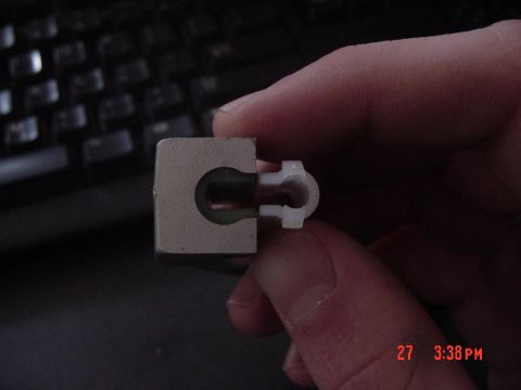 1987 Ford Bronco - A metal and plastic automotive part is held for inspection.