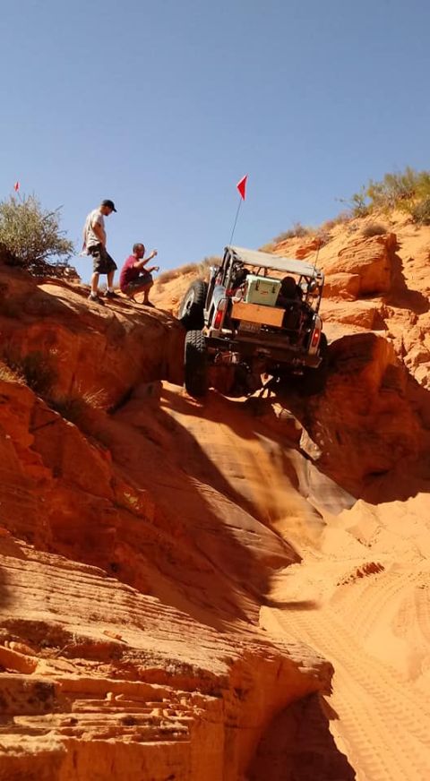 1979 Ford Bronco - Two people watch as an off-road vehicle navigates a challenging sandy terrain.