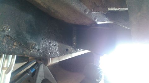 1978 Ford Bronco - Close-up view of vehicle undercarriage components, including frame and suspension, supported by jack stands.