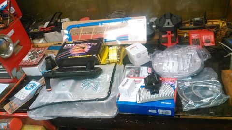 1991 Ford F-150 - A collection of automotive parts, including a transmission pan, filter, and gaskets, laid out on a workbench.