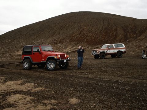 1996 Ford Bronco - Two off-road vehicles, a Jeep Wrangler and a Chevrolet K5 Blazer, are parked on a dirt terrain.