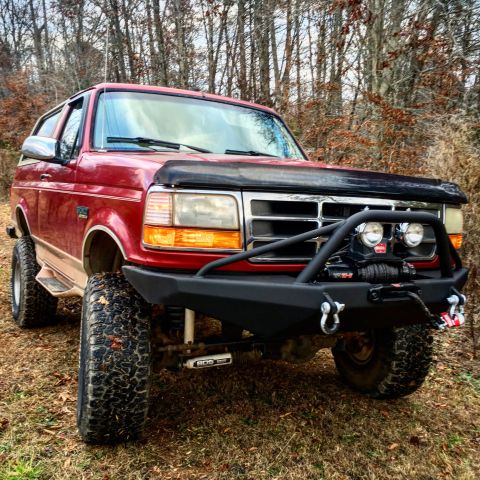1995 Ford Bronco - This red Ford Bronco features a custom winch bumper and off-road tires, suggesting a model year earlier than 1995.