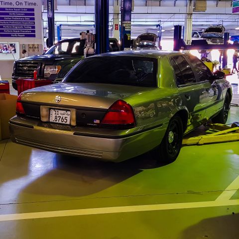 2001 Mercury Grand Marquis - A green 2001 Mercury Grand Marquis is shown on a lift in a service bay, with a Ford F-150 parked behind it.