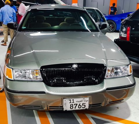 2001 Mercury Grand Marquis - Silver Mercury Grand Marquis parked indoors, showing its front grille and headlights. Other vehicles are visible in the background.