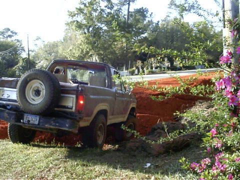 1985 Ford Bronco - Ford Bronco navigates a dirt path with a spare tire mounted on the rear.