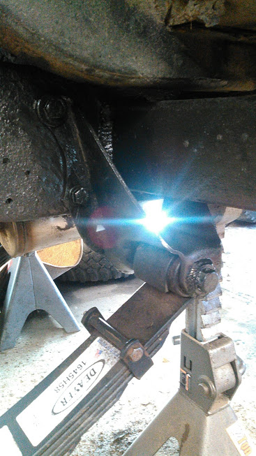 1978 Ford Bronco - Close-up of a vehicle's leaf spring suspension system, showing a part with visible text and a Supermotors logo.