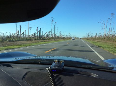 1992 Ford Bronco - Driving past a landscape devastated by severe weather, with snapped trees lining the highway.