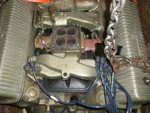 1956 Lincoln Continental - Close-up view of an engine, showing the carburetor intake and spark plug wires, suspended by chains.