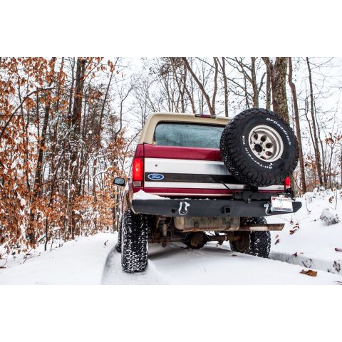 1995 Ford Bronco - Rear view of a 1995 Ford Bronco driving on a snow-covered trail.