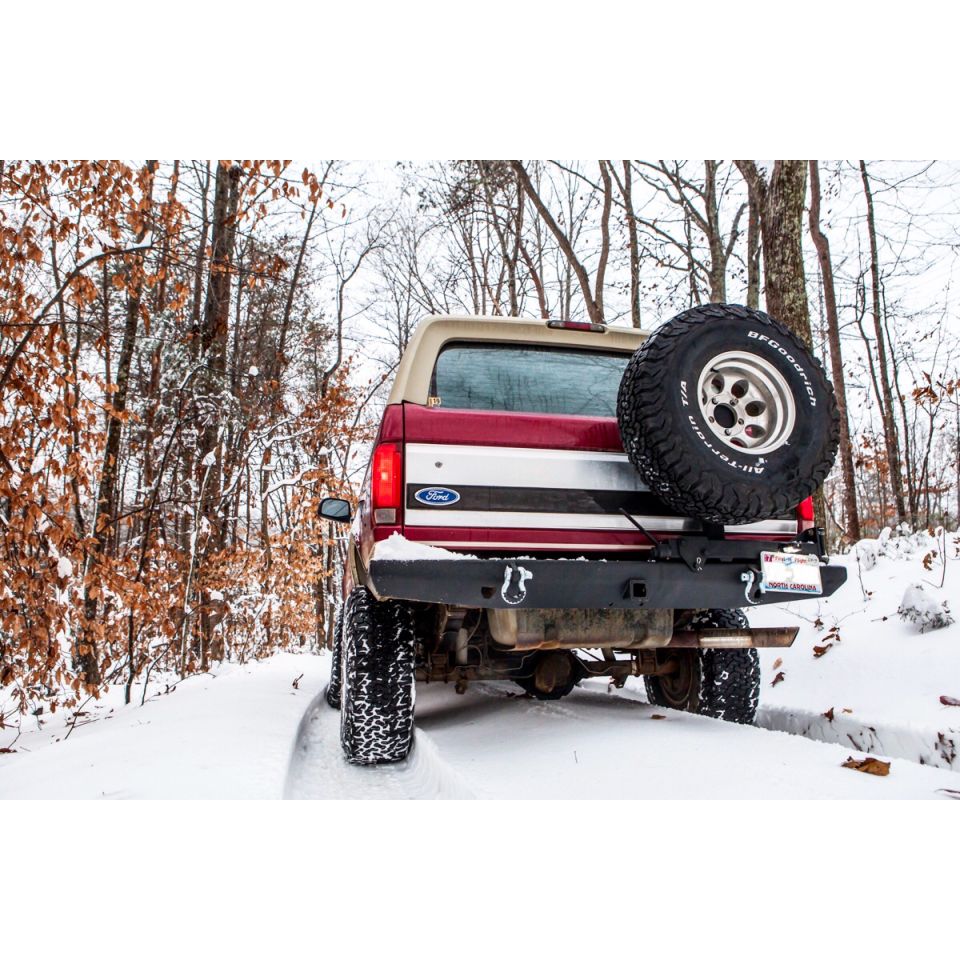 1995 Ford Bronco rear view in snowy woods with spare tire mounted on back