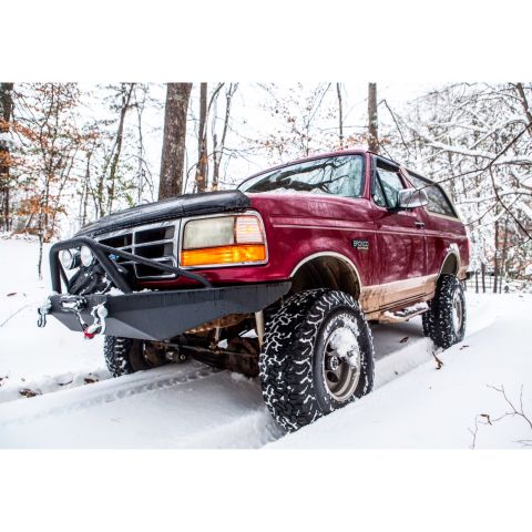1995 Ford Bronco - A red Ford Bronco navigates a snowy trail through a wooded area.