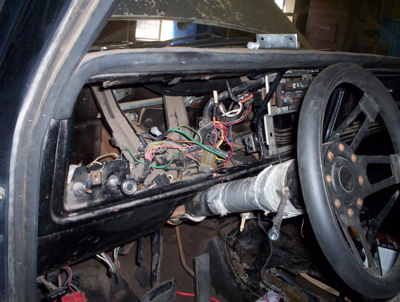 Car interior showing exposed dashboard wiring and steering wheel