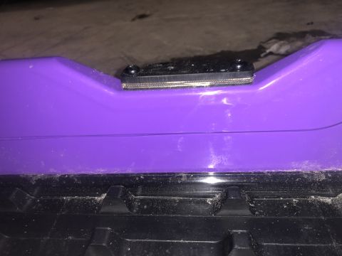 2019 Arctic Cat Mountain Cat 800 - Close-up of a purple snowmobile component, showing a black mounting bracket and part of the track system.