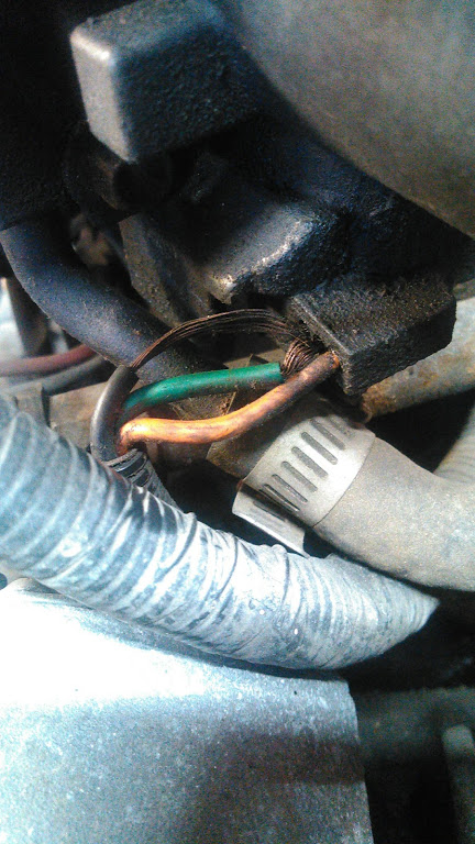 1991 Ford F-150 - Detail of engine compartment wiring, showing exposed copper and green wire strands near a hose clamp.