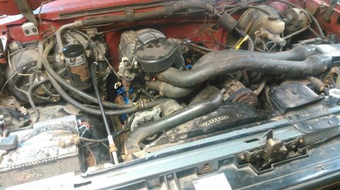 1991 Ford F-150 - The engine bay of a 1991 Ford F-150 is visible, with various hoses and mechanical parts.
