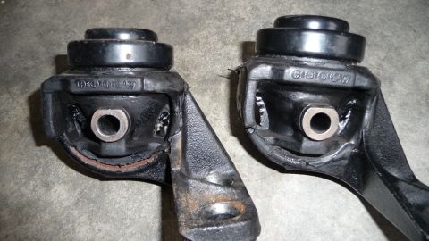 1993 Mazda MX-3 - Close-up of two engine mounts, possibly for a Mazda MX-3, showing stamped markings.