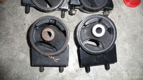1993 Mazda MX-3 - Comparison of worn and new engine mounts, likely for a Mazda vehicle.