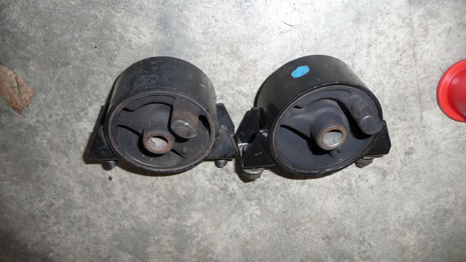Two black engine mounts on a concrete surface